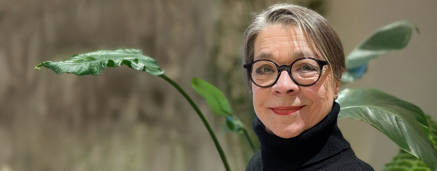 Frau Wenger lächelt vor grüner Zimmerpflanze – Alltagsbegleitung in München.